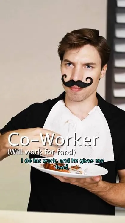 A man in a fake moustache with a paper towel tucked in as a bib, holding up a plate of food
