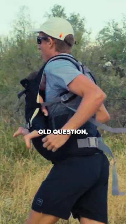 A man running on a trail with a toddler in a carrier on his chest